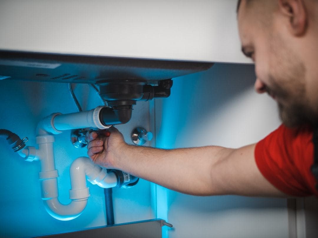 Plumber repairing pipes under a sink